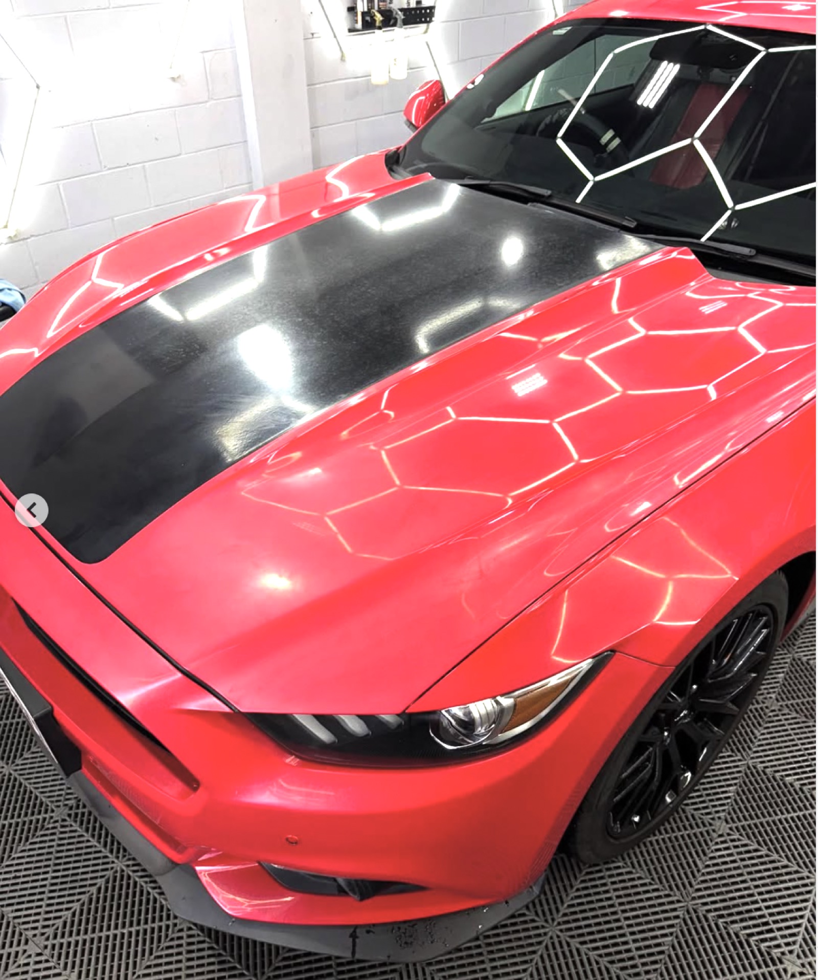 Red Mustang bonnet with hexagonal light reflections after ceramic coating